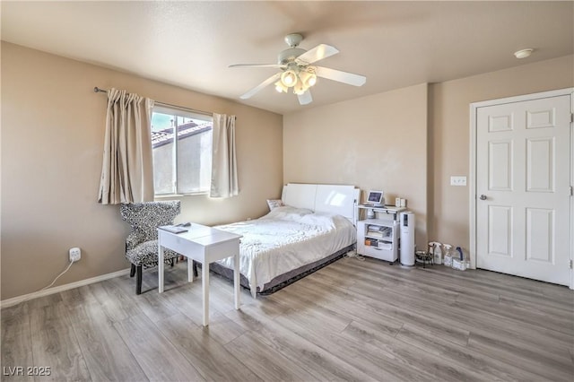 bedroom with a ceiling fan, baseboards, and wood finished floors