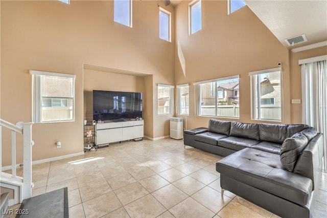 living room with visible vents, baseboards, light tile patterned floors, and a high ceiling