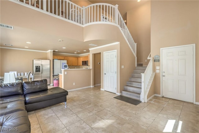 living area with recessed lighting, visible vents, stairway, and a towering ceiling