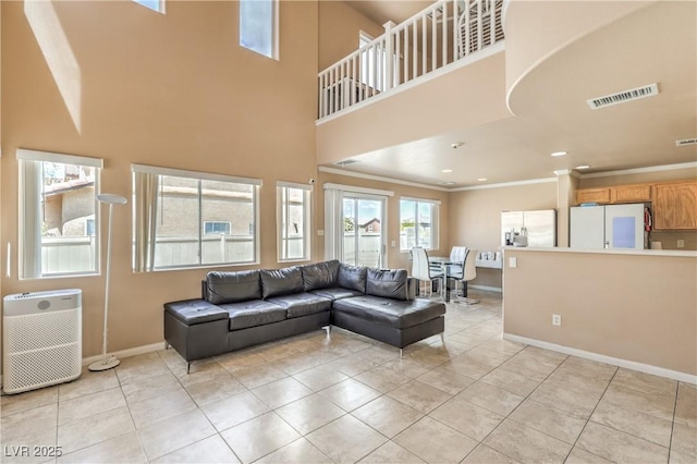 living area with crown molding, light tile patterned flooring, baseboards, and a towering ceiling