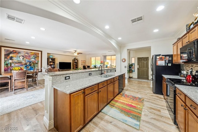 kitchen with crown molding, visible vents, a sink, and black appliances