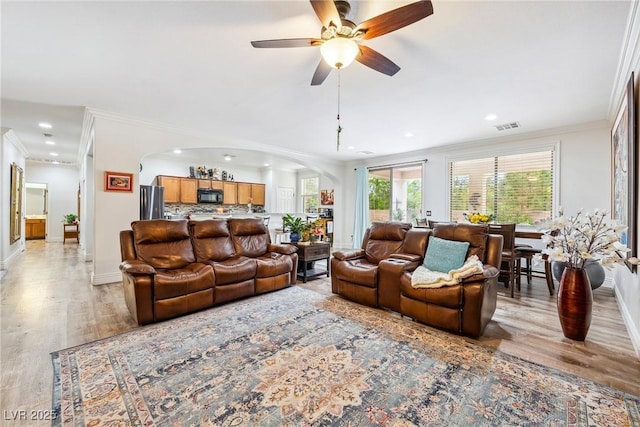 living room featuring baseboards, arched walkways, visible vents, and recessed lighting