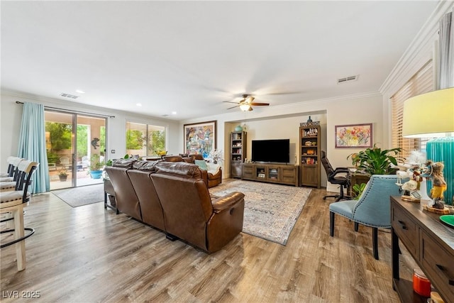 living room featuring crown molding, light wood finished floors, ceiling fan, and visible vents