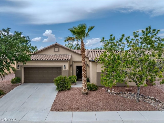 mediterranean / spanish house featuring a garage, stucco siding, concrete driveway, and a tiled roof