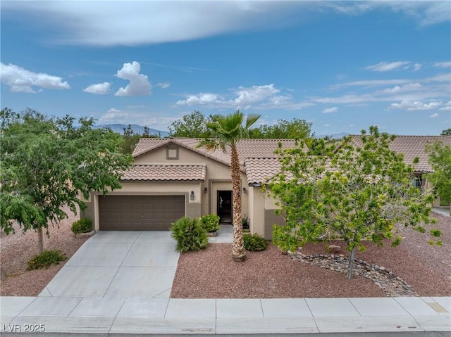 view of front of house with a tile roof, a garage, stucco siding, a mountain view, and driveway