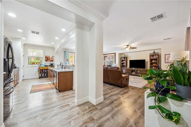living area featuring a ceiling fan, visible vents, and ornamental molding