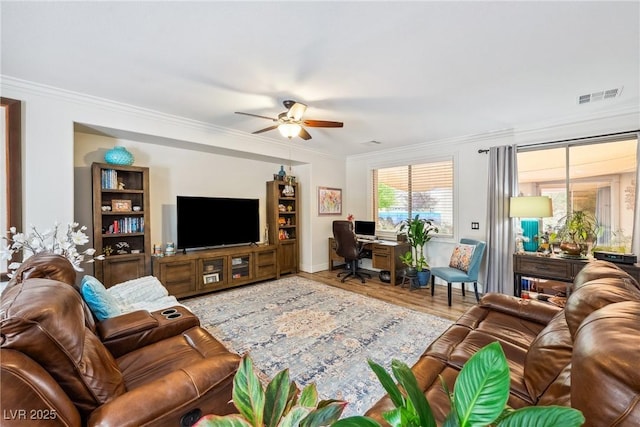 living area with ceiling fan, visible vents, crown molding, wood finished floors, and baseboards