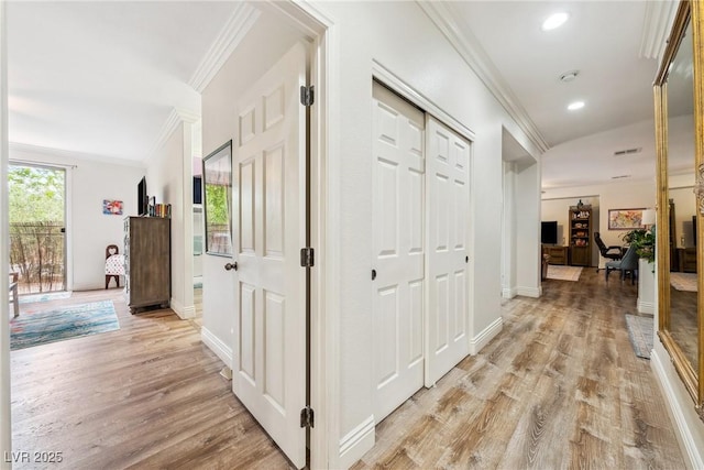 hallway with crown molding, light wood-style floors, baseboards, and visible vents
