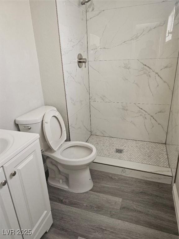 bathroom featuring vanity, toilet, wood finished floors, and a stall shower
