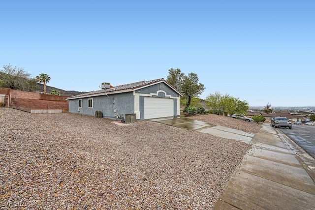 view of home's exterior with a tile roof, an attached garage, stucco siding, and driveway