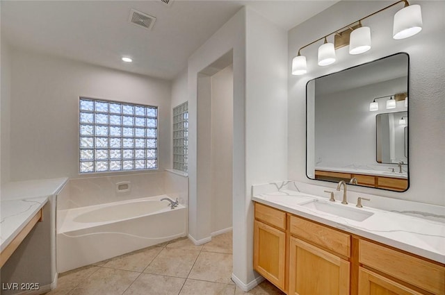 bathroom featuring visible vents, vanity, baseboards, tile patterned floors, and a bath