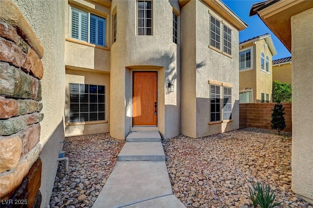 property entrance with stucco siding and fence