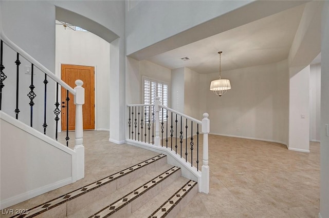 stairs with visible vents, baseboards, tile patterned floors, a chandelier, and arched walkways