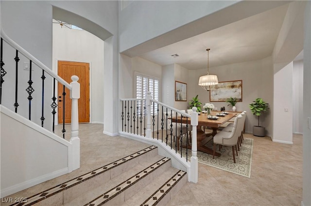 interior space with visible vents, arched walkways, baseboards, an inviting chandelier, and stairs