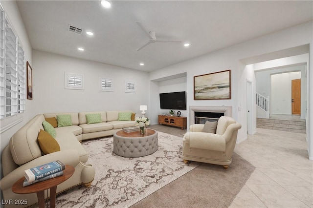 living area featuring a ceiling fan, visible vents, tile patterned flooring, a glass covered fireplace, and recessed lighting