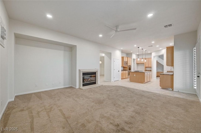 unfurnished living room with visible vents, a ceiling fan, recessed lighting, and light carpet