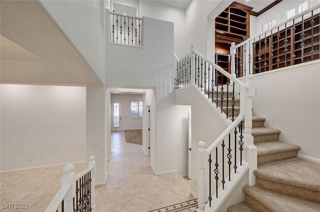 staircase featuring tile patterned floors, a high ceiling, and baseboards