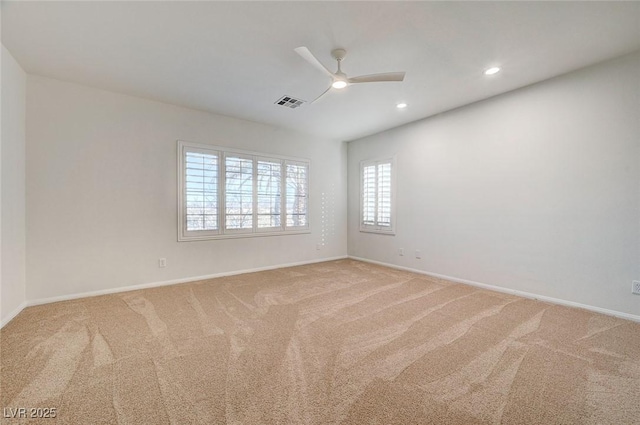 unfurnished room with a ceiling fan, light colored carpet, visible vents, and baseboards