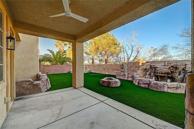 view of patio / terrace with a fenced backyard, a ceiling fan, and an outdoor fire pit