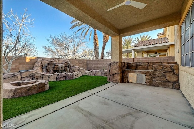 view of patio with a fenced backyard, ceiling fan, and an outdoor fire pit