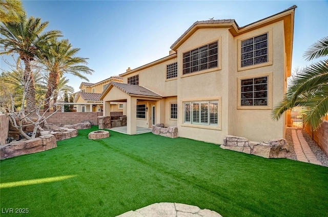 rear view of house featuring a yard, a fenced backyard, and stucco siding
