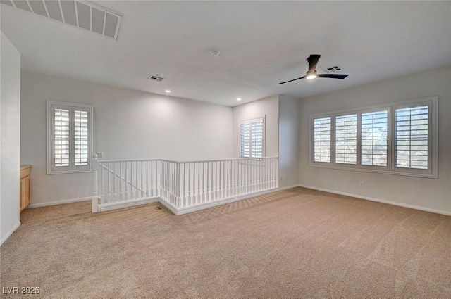 spare room featuring carpet floors, ceiling fan, baseboards, and a healthy amount of sunlight