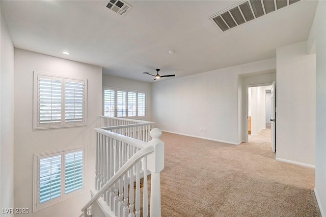 corridor featuring baseboards, visible vents, carpet floors, and an upstairs landing