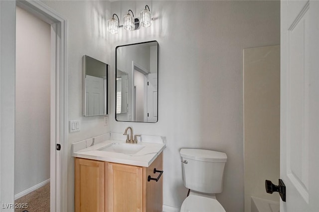 bathroom featuring toilet, baseboards, and vanity