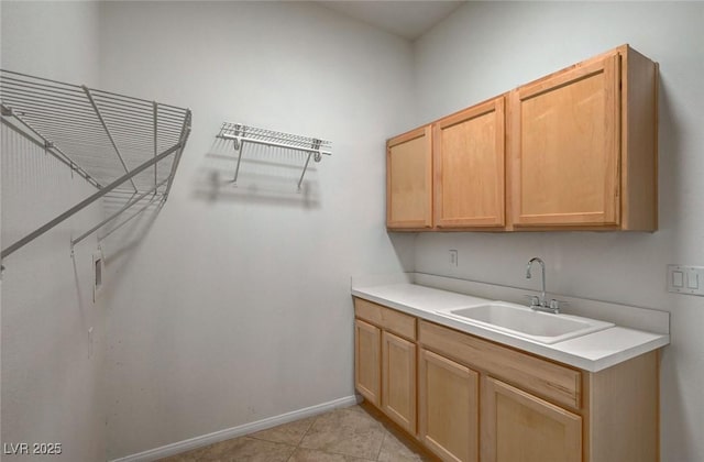 washroom with a sink, baseboards, and light tile patterned flooring