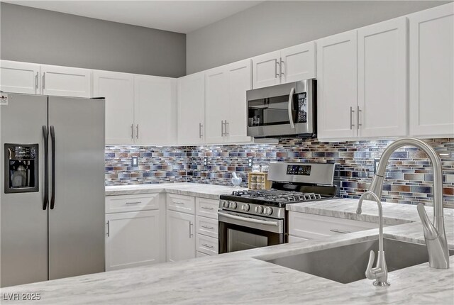 11249 Revelry Ln, Las Vegas, NV 89138 - kitchen featuring light stone counters, a sink, white cabinets, and stainless steel appliances