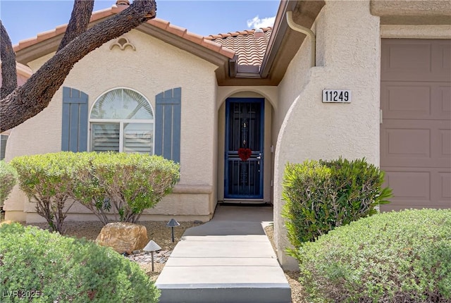 11249 Revelry Ln, Las Vegas, NV 89138 - property entrance with a tiled roof, an attached garage, and stucco siding