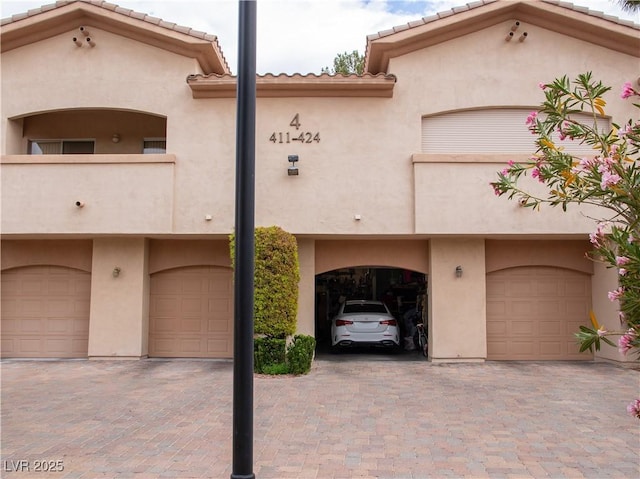 2050 W Warm Springs Rd Unit 411, Henderson, NV 89014 - view of front of home with stucco siding, driveway, a tile roof, and a garage