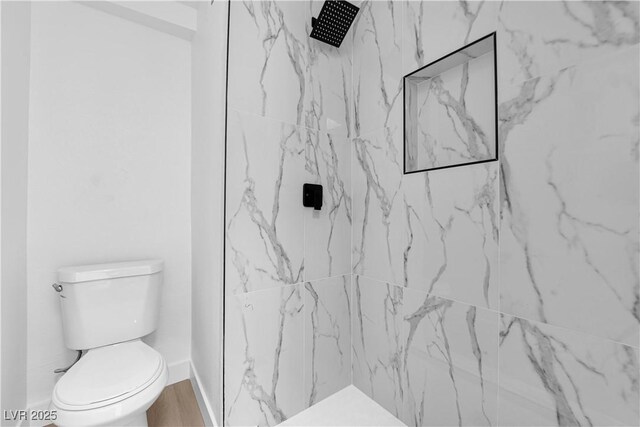 full bathroom with a marble finish shower, baseboards, and toilet
