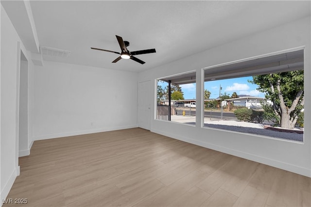empty room featuring visible vents, a ceiling fan, light wood-style flooring, and baseboards