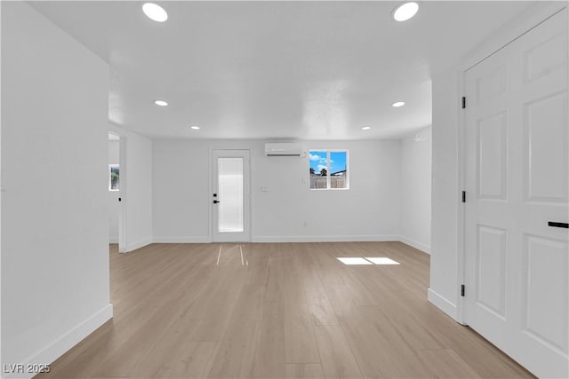 interior space featuring baseboards, a wall mounted AC, recessed lighting, and light wood finished floors