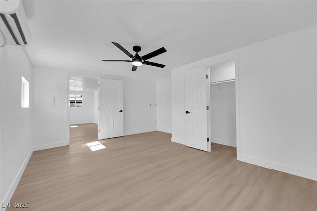 unfurnished bedroom with baseboards, ceiling fan, light wood-style flooring, and a spacious closet