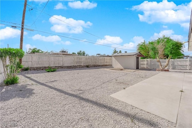 view of yard with a storage shed, a patio, an outbuilding, and a fenced backyard