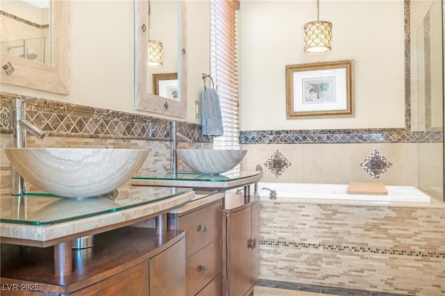 bathroom with double vanity, tile walls, a sink, and a bath
