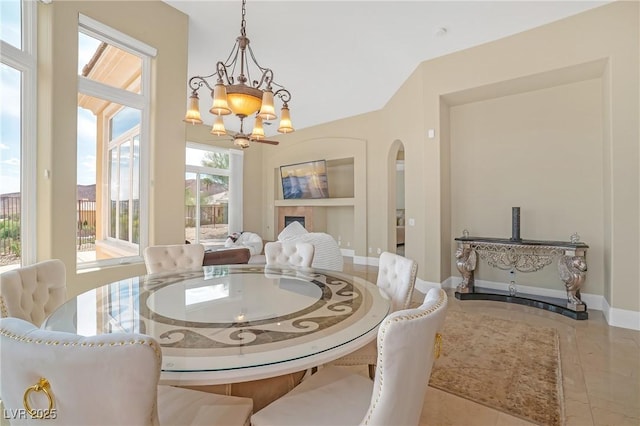 dining space with baseboards, a chandelier, built in shelves, and tile patterned floors