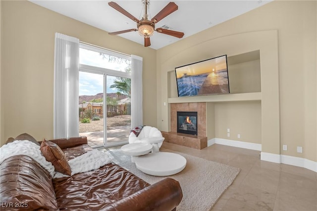living room with a ceiling fan and a tile fireplace