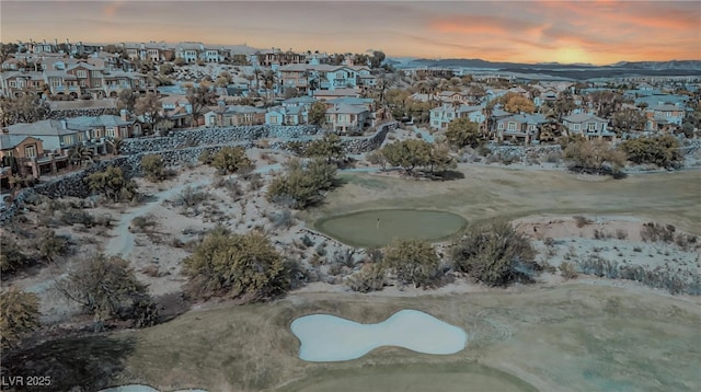 aerial view at dusk featuring view of golf course and a residential view