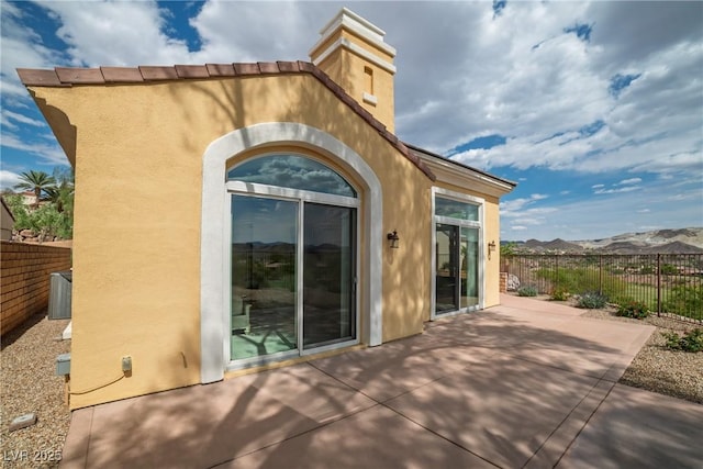 back of property with fence, a mountain view, a patio area, and stucco siding