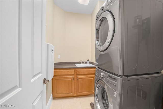laundry area with stacked washer and dryer, cabinet space, and light tile patterned floors