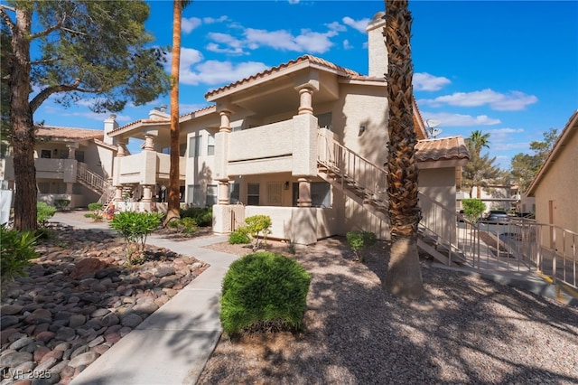 912 Falconhead Ln Unit 101, Las Vegas, NV 89128 - view of front of property featuring fence, stucco siding, a tile roof, a chimney, and stairway