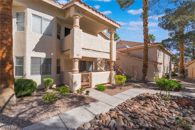 912 Falconhead Ln Unit 101, Las Vegas, NV 89128 - view of front facade featuring stairs, stucco siding, a tiled roof, and fence private yard