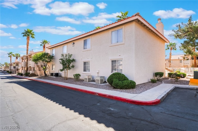 912 Falconhead Ln Unit 101, Las Vegas, NV 89128 - view of side of home with a residential view, cooling unit, a chimney, and stucco siding