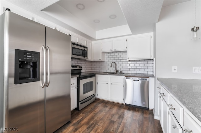 912 Falconhead Ln Unit 101, Las Vegas, NV 89128 - kitchen with white cabinets, appliances with stainless steel finishes, a sink, backsplash, and a tray ceiling