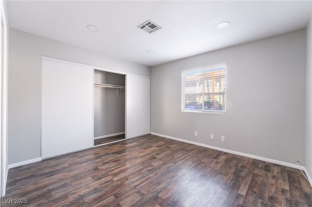 912 Falconhead Ln Unit 101, Las Vegas, NV 89128 - unfurnished bedroom featuring dark wood-style flooring, baseboards, visible vents, and a closet