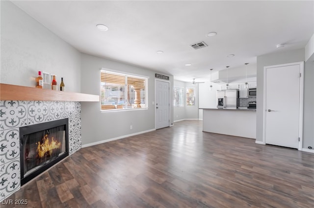 912 Falconhead Ln Unit 101, Las Vegas, NV 89128 - unfurnished living room with a tiled fireplace, recessed lighting, baseboards, visible vents, and dark wood-style floors
