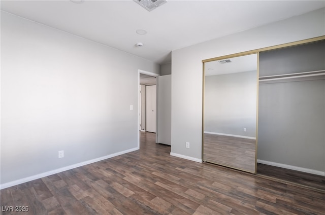 912 Falconhead Ln Unit 101, Las Vegas, NV 89128 - unfurnished bedroom with dark wood-style flooring, baseboards, visible vents, and a closet